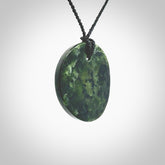 A lovely disc design with cupping on one side and the lightly convex form on the other - a little feature that captures the light and gives the piece a sense of movement and form. Hand made from New Zealand Jade by Ric Moor. Delivered with an adjustable black cord.